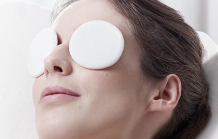 Una mujer relajándose con una máscara de ojos.