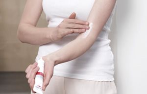 Una mujer aplicándose Eucerin DA Control Crema de Cuidado Intensivo en el codo.