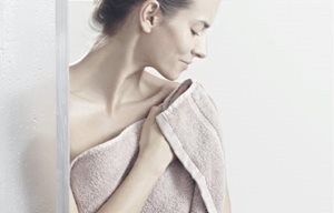 Una mujer secándose la piel con palmaditas después de la ducha.