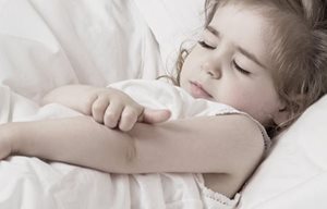 Una niña rascándose el codo.