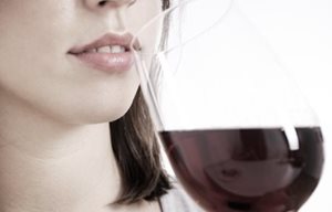 Una mujer bebiendo una copa de vino tinto.