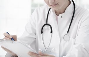 Un médico con el estetoscopio alrededor del cuello, tomando notas.