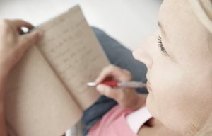 Una mujer escribiendo en un anotador.