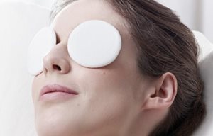 Una mujer relajándose con una máscara de ojos.