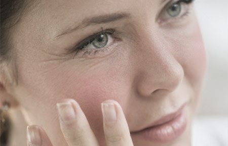 Mujer tocándose la cara con la mano